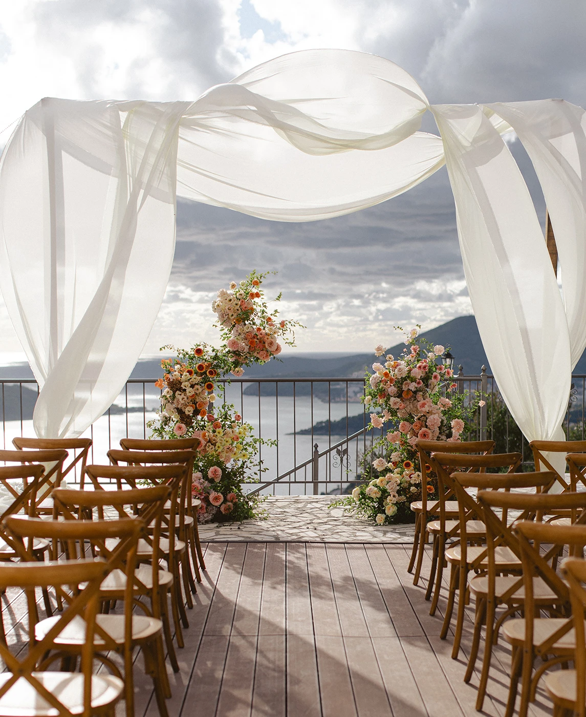 Flottie wedding decor and organisation: portfolio highlights of the Peach Haze wedding project showcasing a draped outdoor ceremony arch, vibrant orange-toned floral centerpieces, and citrus styling