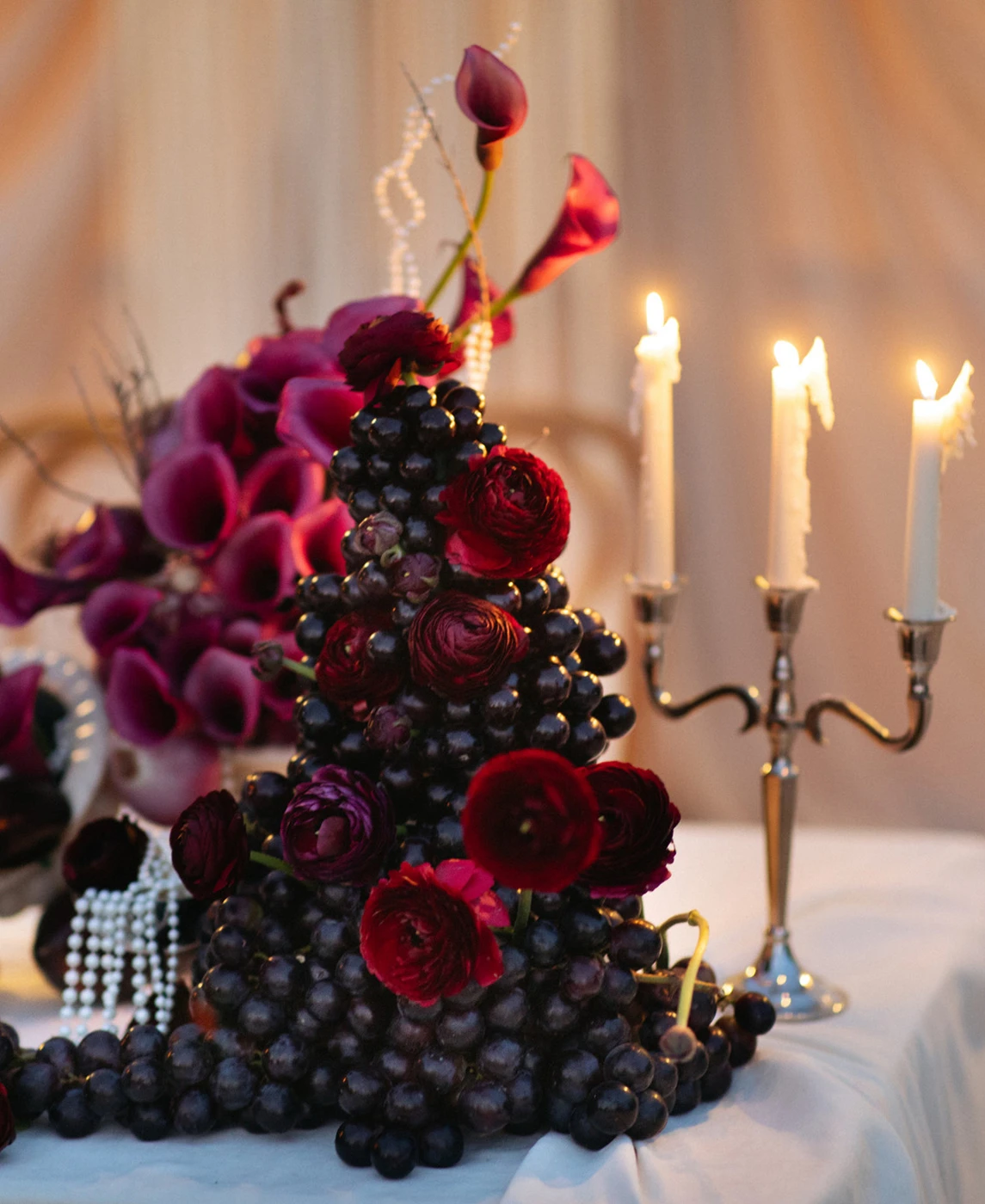 Flottie wedding decor and organisation: dramatic tablescape featuring rich burgundy floral arrangements, dark grapes, eggplants, and a silver candelabra for the Shades of Burgundy project