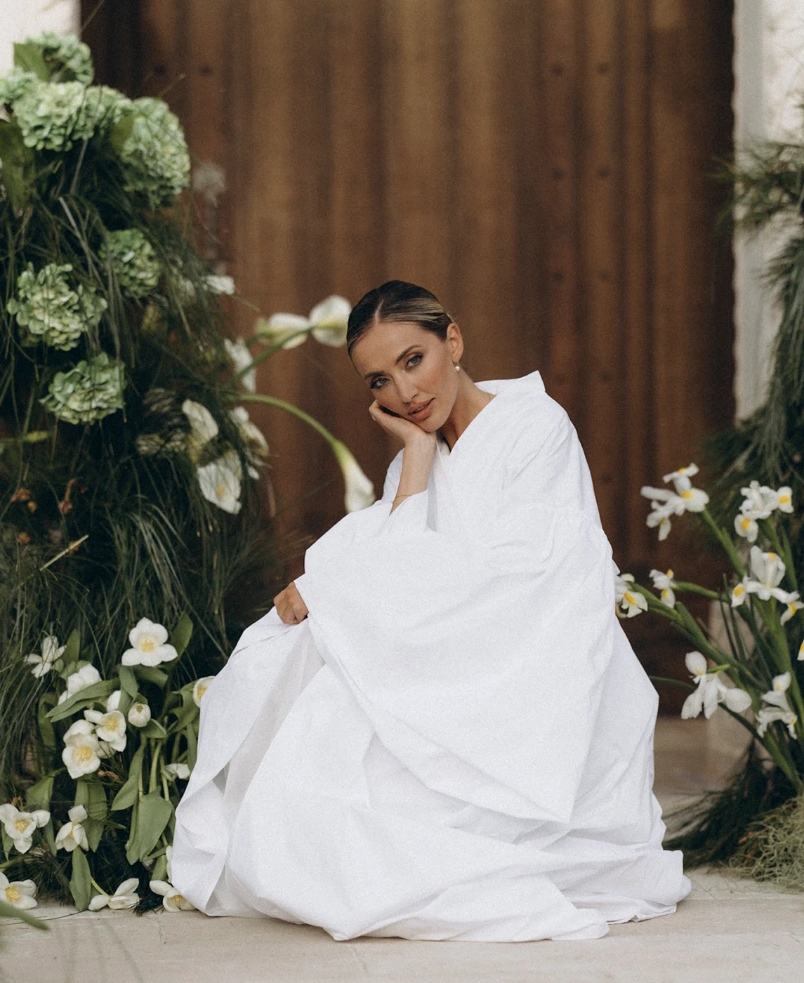 Flottie wedding decor and organisation: elegant bride in a white gown sitting amidst lush green installations and white floral arrangements for the Soul Vibes wedding project